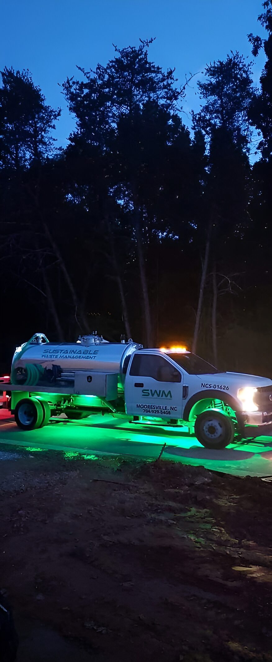 SWM service truck glowing with green lights during nighttime operation in the woods.
